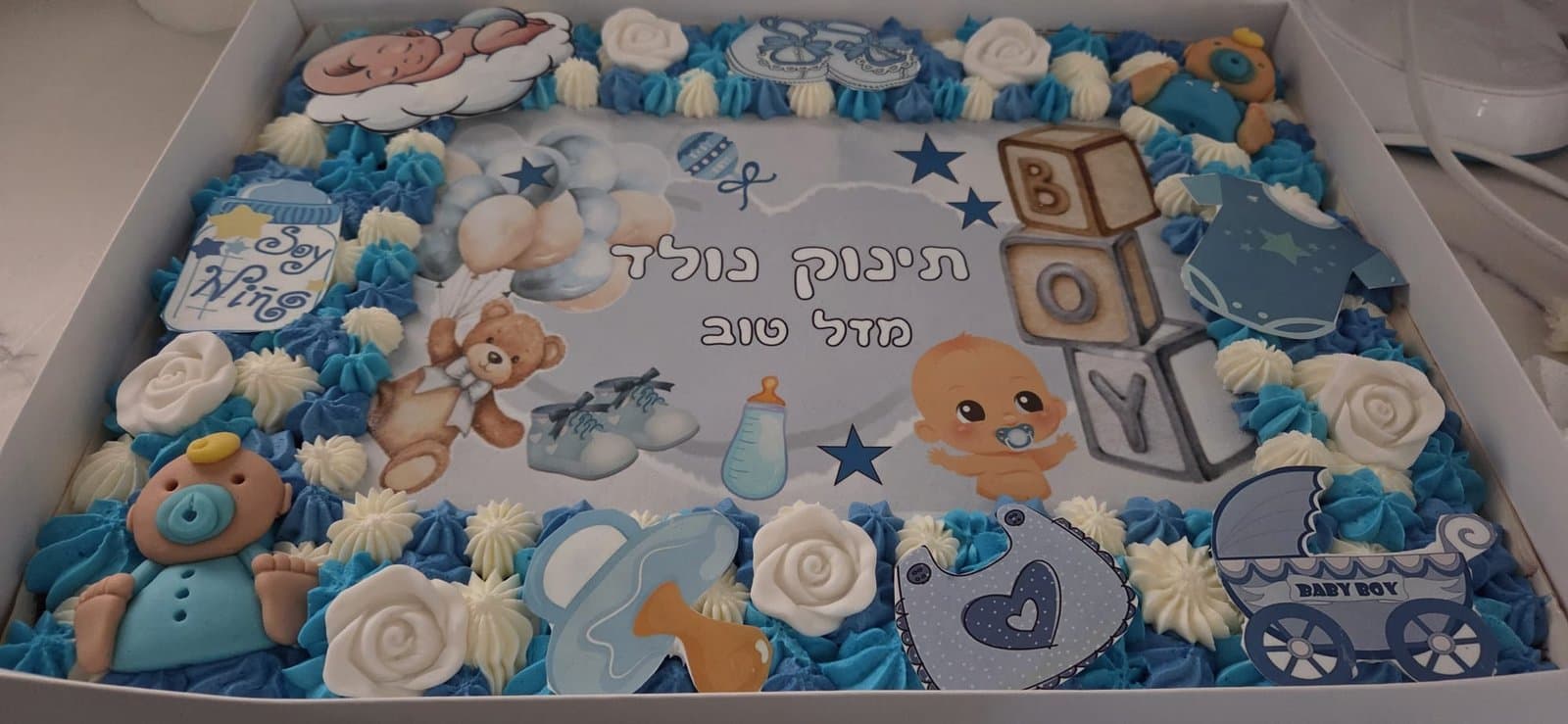 דף סוכר בגווני כחול עם דובי ועגלה, מסגרת קצפת כחולה ולבנה עם ורדים ותינוק מסוכר