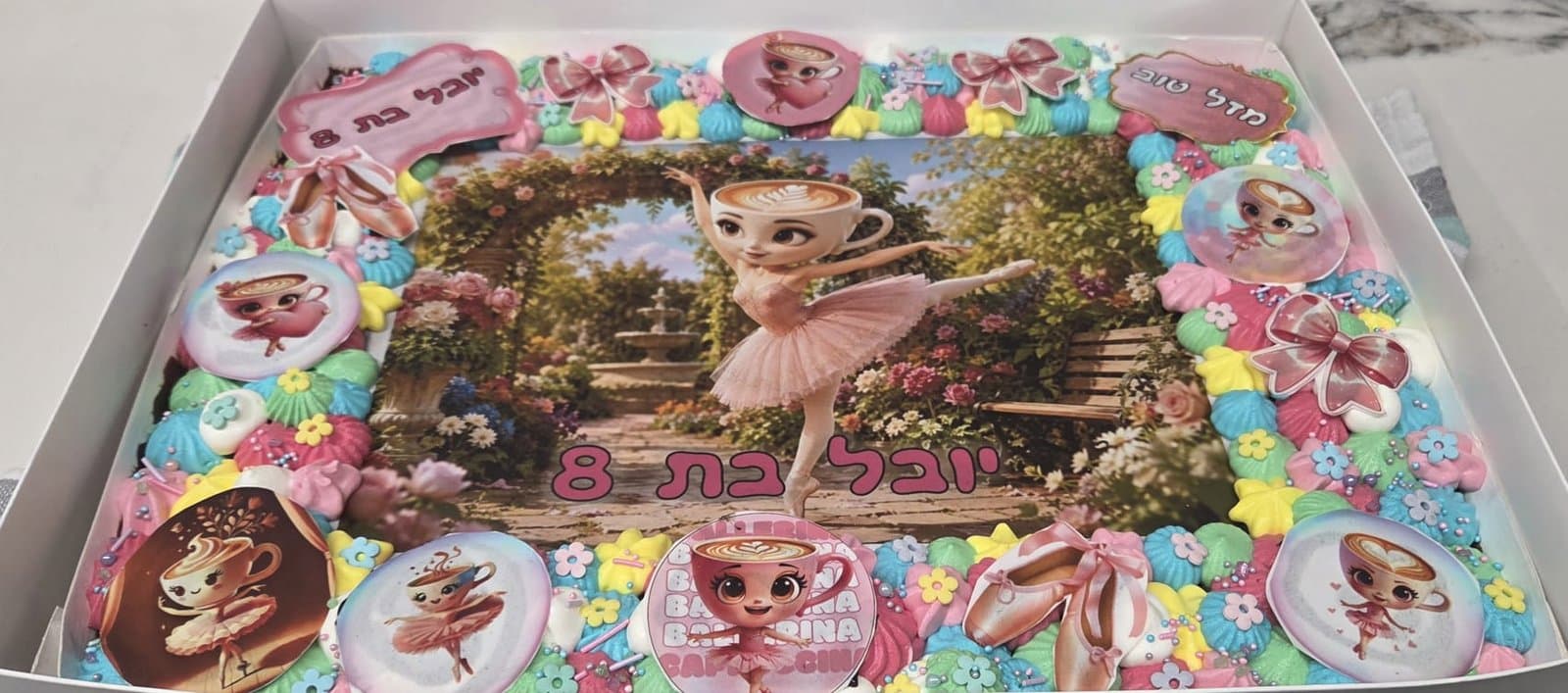 דף סוכר של בלרינה בדמות כוס קפה בגן פרחים, מסגרת קצפת בצבעי פסטל ונעלי בלט