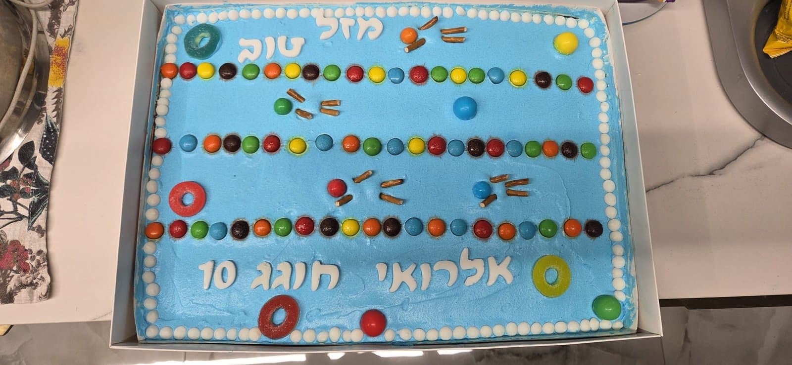 קצפת תכולה חלקה עם שורות סוכריות צבעוניות, טבעות גומי ואותיות מסוכר של מזל טוב