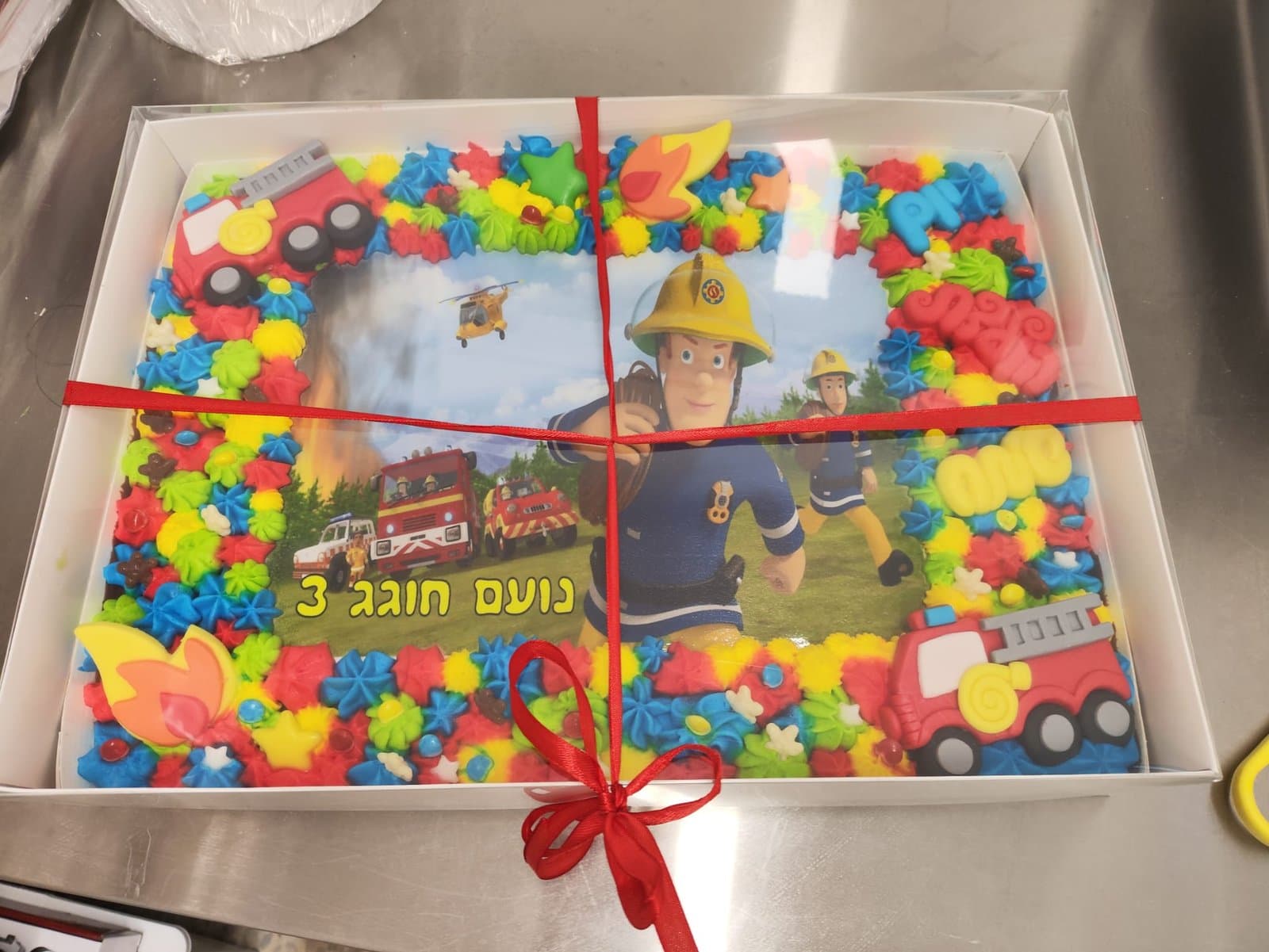 דף סוכר של כבאי סם, מסגרת קצפת צבעונית עם כבאית ולהבות מסוכר ועטיפת סרט אדום