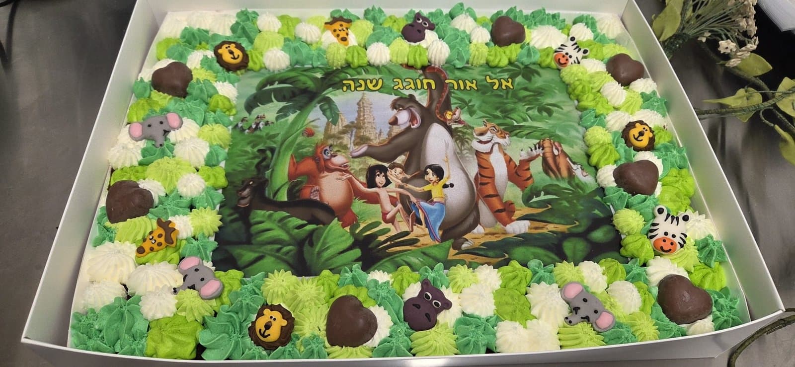 דף סוכר של ספר הג'ונגל, מסגרת קצפת בגווני ירוק עם לבבות שוקולד וחיות סוכר
