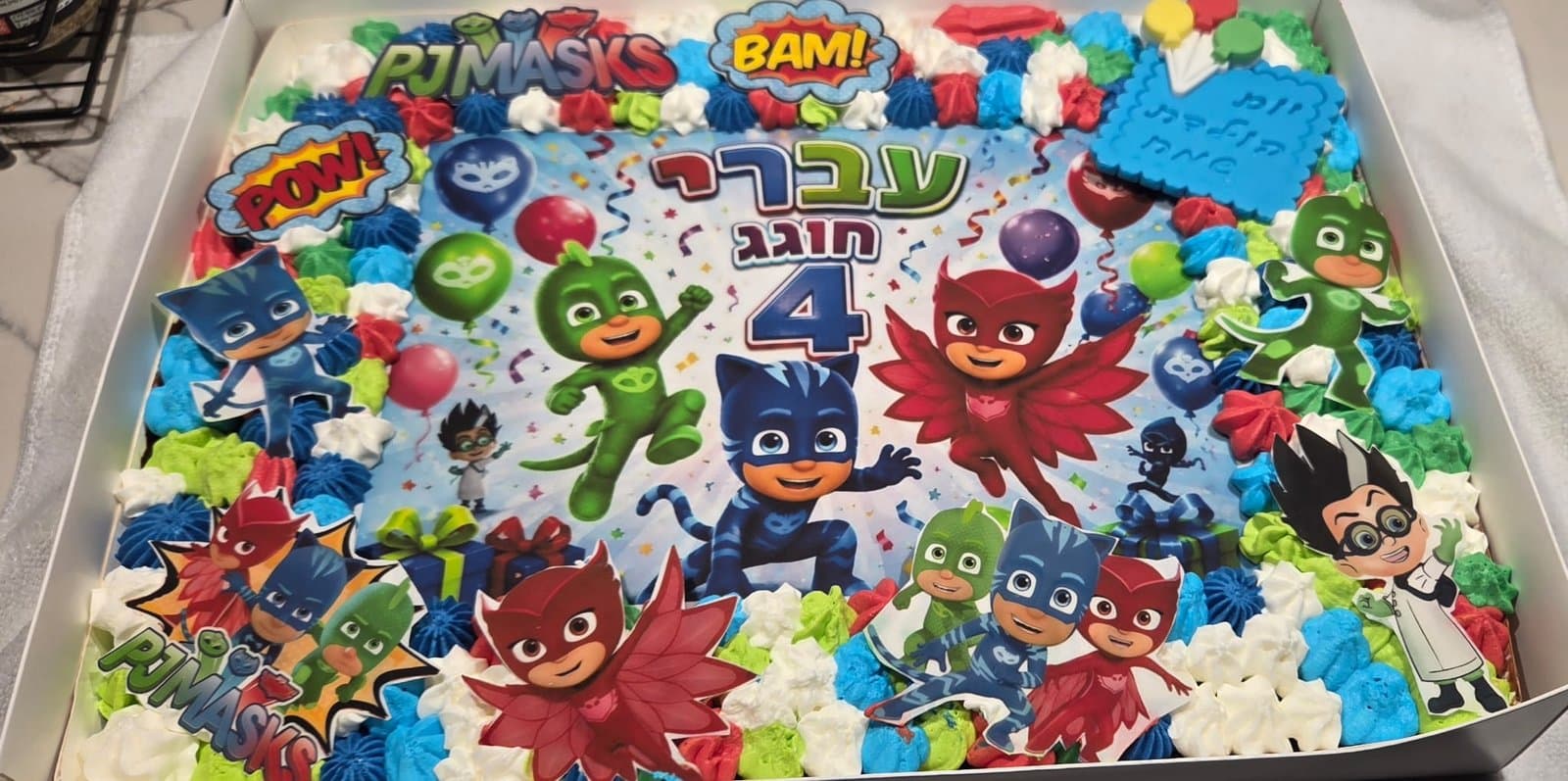 דף סוכר של גיבורי הפיג'מות עם בלונים, מסגרת שושנות קצפת באדום, כחול וירוק ודמויות אכילות