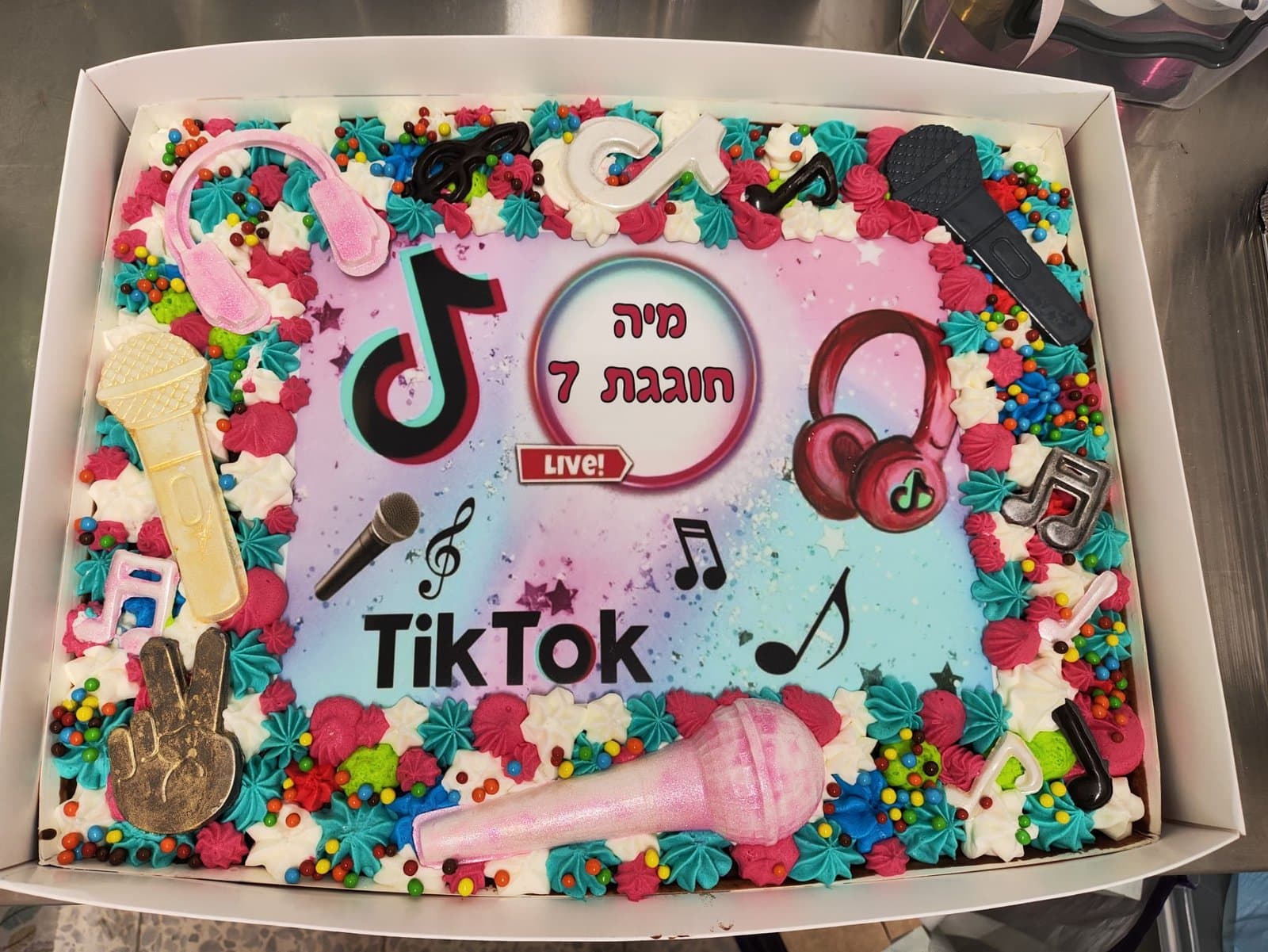 דף סוכר של טיקטוק עם אוזניות ותווים, מסגרת קצפת צבעונית ומיקרופונים מסוכר